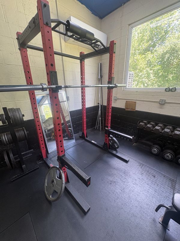 Red power rack with barbell and dumbbells by the window