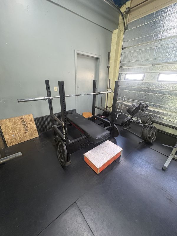 Squat rack, bench and dumbbells by the window